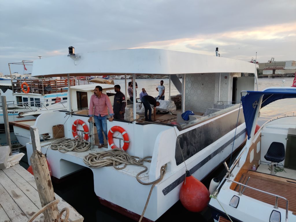 catamaran sur les eaux tunisiennes à Sfax plus précisément. Ce catamaran est un ferry pour le travail. Il est blanc et est amarré.